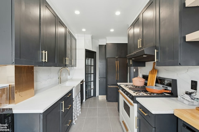 31-28 56th St, New York City, NY 11377 - kitchen with under cabinet range hood, white gas range, tasteful backsplash, light tile patterned floors, and light countertops
