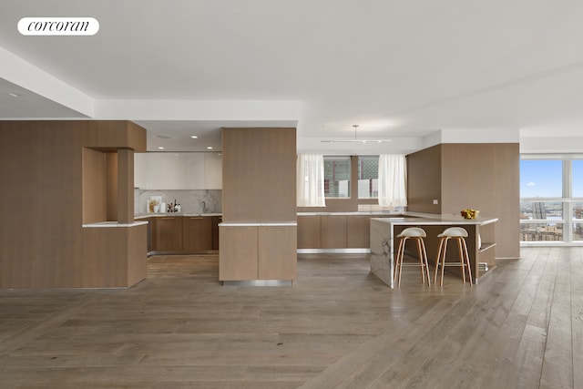 146 W 57th St Pha, Pha, New York City, NY 10019 - kitchen with modern cabinets, light wood-type flooring, tasteful backsplash, and a breakfast bar area
