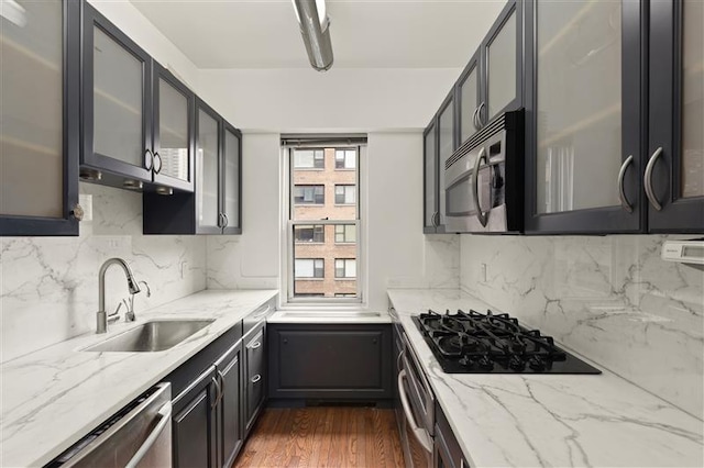 340 E 64th St Unit 9-B, New York City, NY 10065 - kitchen featuring stainless steel appliances, glass insert cabinets, light stone countertops, and dark wood-style floors