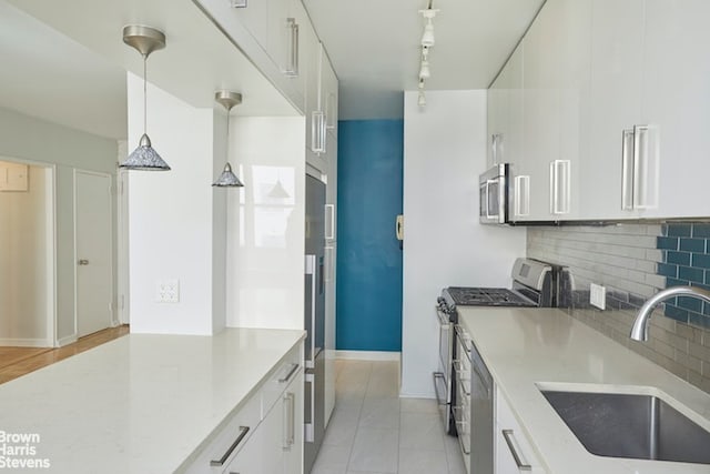 63 E 9th St Unit 9G, New York City, NY 10003 - kitchen featuring stainless steel appliances, backsplash, white cabinetry, light tile patterned flooring, and decorative light fixtures