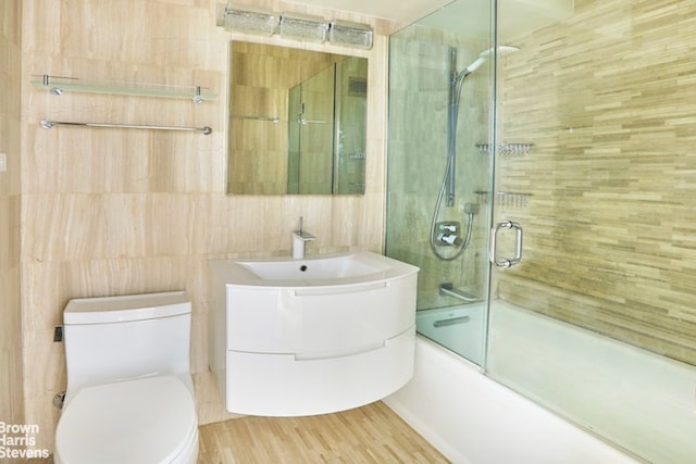 63 E 9th St Unit 9G, New York City, NY 10003 - full bathroom featuring tile walls, shower / bath combination with glass door, vanity, and wood finished floors