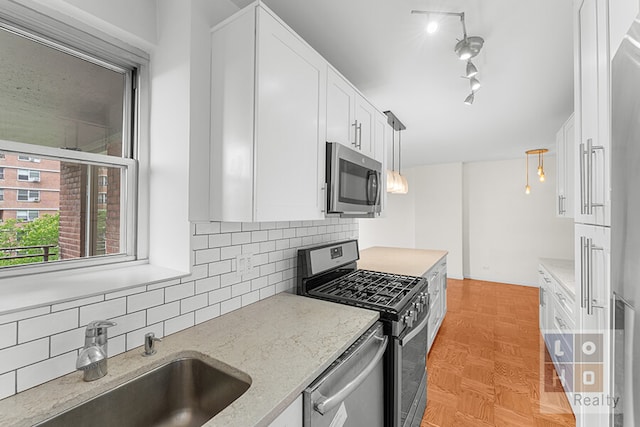 457 Fdr Dr Unit A604, New York City, NY 10002 - kitchen with stainless steel appliances, white cabinets, backsplash, light stone counters, and decorative light fixtures