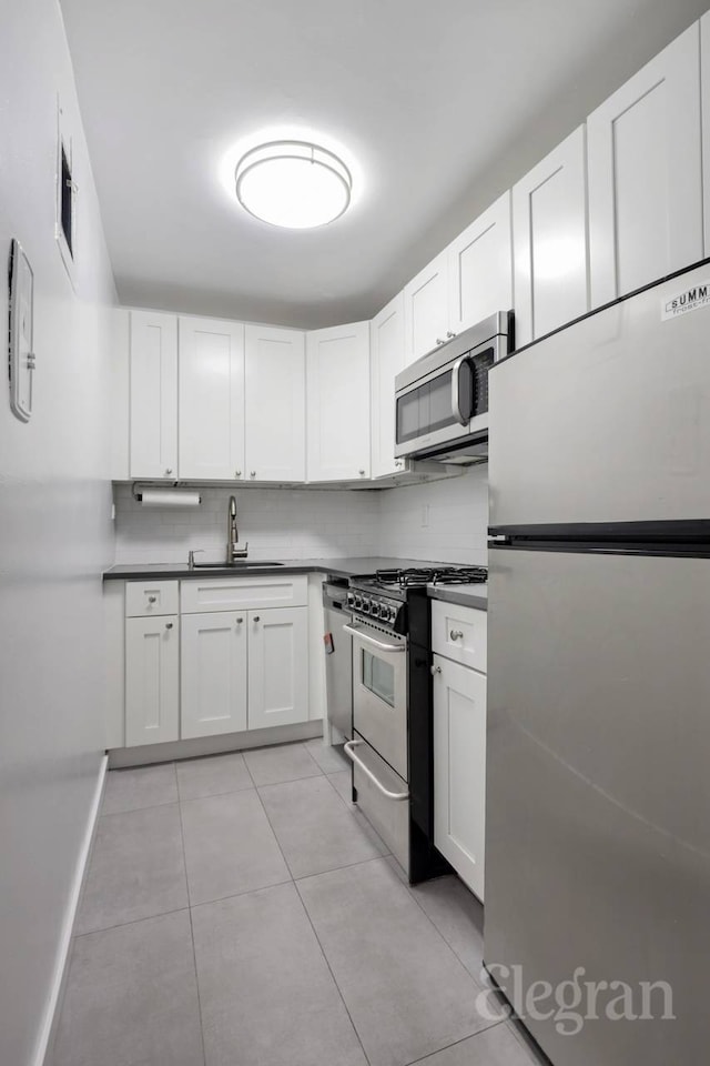 333 E 14th St Unit 5L, New York City, NY 10003 - kitchen featuring stainless steel appliances, light tile patterned floors, white cabinetry, decorative backsplash, and dark countertops