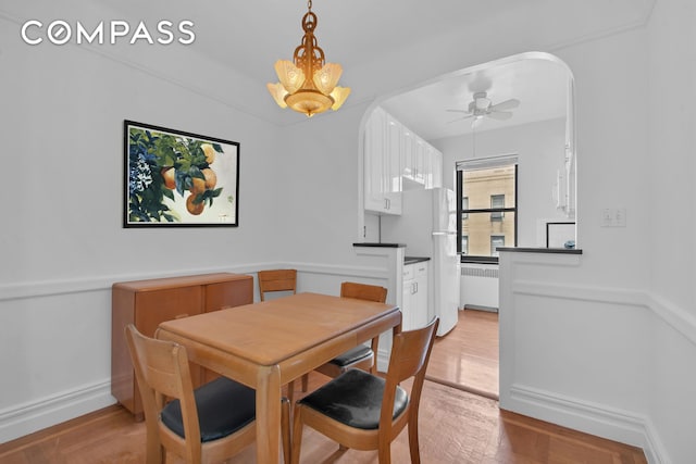 200 Pinehurst Ave Unit 5C, New York City, NY 10033 - dining space with radiator, arched walkways, light wood-style floors, and ceiling fan