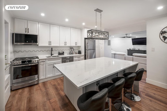 34-10 94th St Unit 1A, New York City, NY 11372 - kitchen featuring appliances with stainless steel finishes, a center island, white cabinets, a breakfast bar, and crown molding