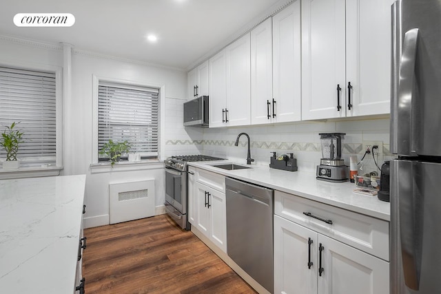 34-10 94th St Unit 1A, New York City, NY 11372 - kitchen featuring appliances with stainless steel finishes, radiator, backsplash, white cabinetry, and crown molding