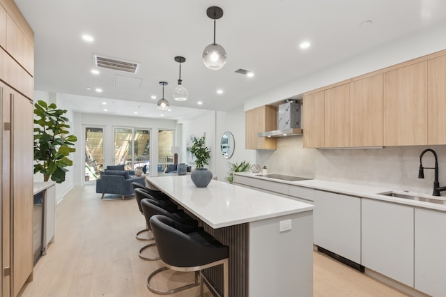 53 W 119th St Unit 1, New York City, NY 10026 - kitchen featuring light brown cabinets, modern cabinets, wall chimney exhaust hood, black electric stovetop, and recessed lighting