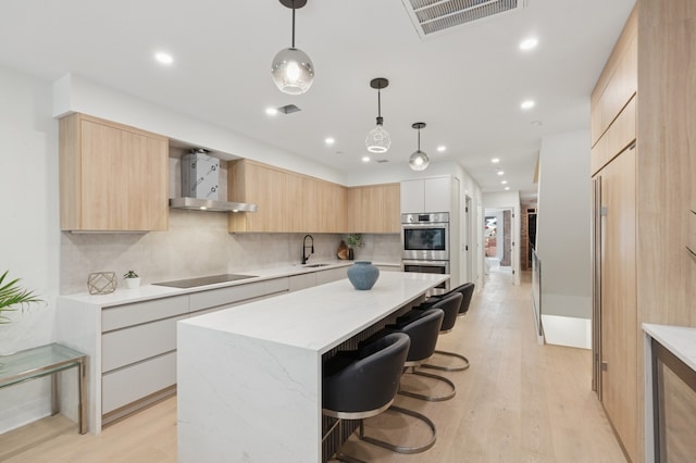 53 W 119th St Unit 1, New York City, NY 10026 - kitchen featuring wall chimney exhaust hood, modern cabinets, light brown cabinetry, double oven, and black electric stovetop