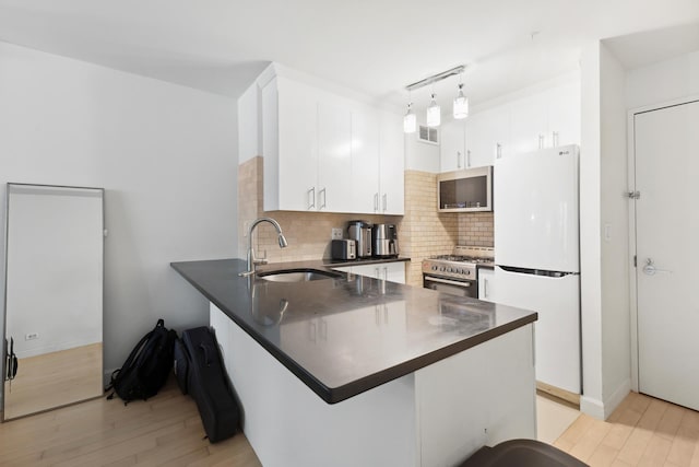 322 W 57th St Unit 18J, New York City, NY 10019 - kitchen featuring stainless steel appliances, dark countertops, a peninsula, light wood-style flooring, and backsplash