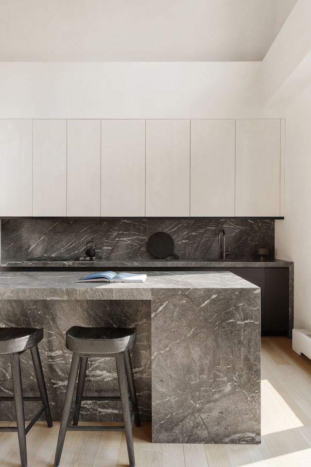415 Washington St Unit 5A, New York City, NY 10013 - kitchen featuring modern cabinets, dark stone countertops, white cabinets, decorative backsplash, and a kitchen bar