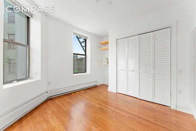 305 W 150th St Unit 511, New York City, NY 10039 - unfurnished bedroom featuring baseboard heating, light wood-style floors, and a closet