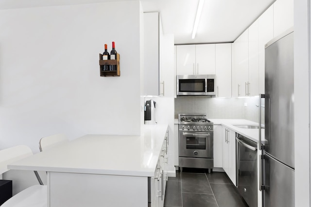 240 E 76th St Unit 3W, New York City, NY 10021 - kitchen featuring stainless steel appliances, a peninsula, tasteful backsplash, and white cabinets