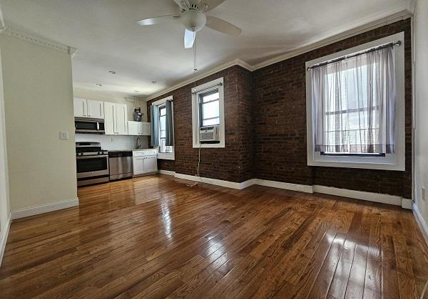 21-67 33rd St Unit F-4, New York City, NY 11105 - unfurnished living room with ceiling fan, dark wood-type flooring, crown molding, cooling unit, and brick wall