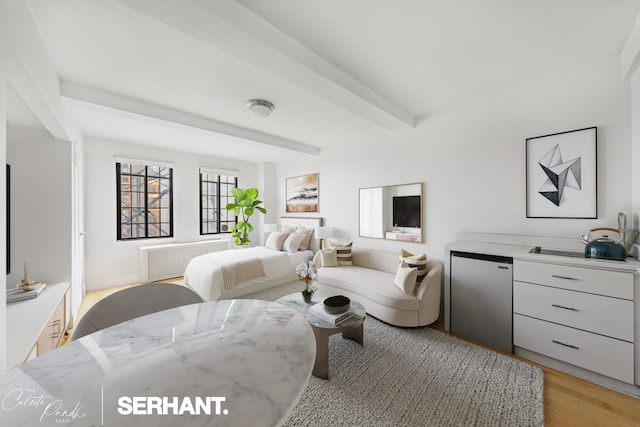 320 E 42nd St Unit 705, New York City, NY 10017 - bedroom with radiator heating unit, light wood-type flooring, beamed ceiling, and stainless steel fridge