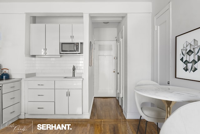 320 E 42nd St Unit 705, New York City, NY 10017 - kitchen with stainless steel microwave, light countertops, wood finished floors, white cabinets, and backsplash