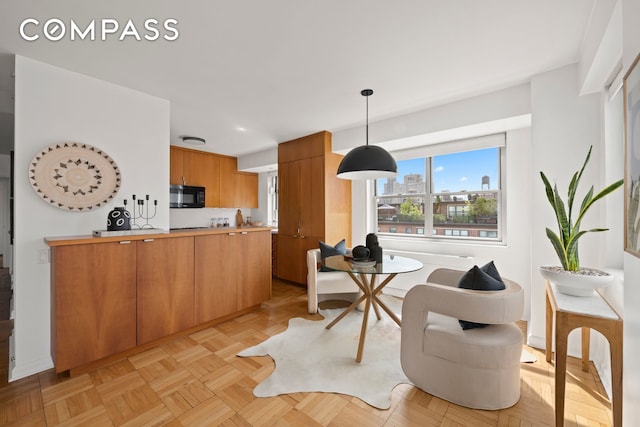 70 E 10th St Unit 15R, New York City, NY 10003 - kitchen with black microwave, a peninsula, light countertops, pendant lighting, and brown cabinets