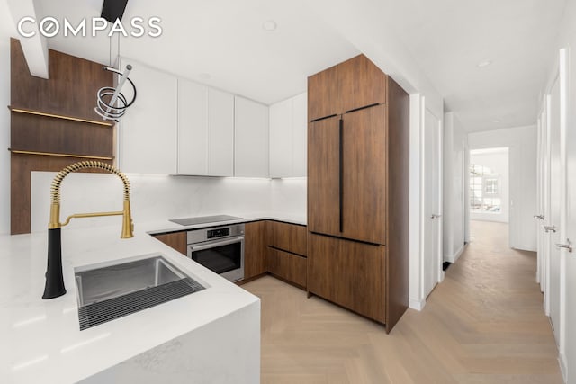 90 Herbert St Unit Th1, New York City, NY 11222 - kitchen with stainless steel oven, modern cabinets, black electric cooktop, paneled built in refrigerator, and light countertops