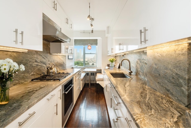 12 Beekman Pl Unit 11B, New York City, NY 10022 - kitchen with under cabinet range hood, appliances with stainless steel finishes, light stone countertops, dark wood-style flooring, and white cabinets