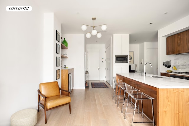509 Pacific St Unit 4J, New York City, NY 11217 - kitchen featuring stainless steel microwave, light wood-style floors, a kitchen bar, modern cabinets, and light stone countertops