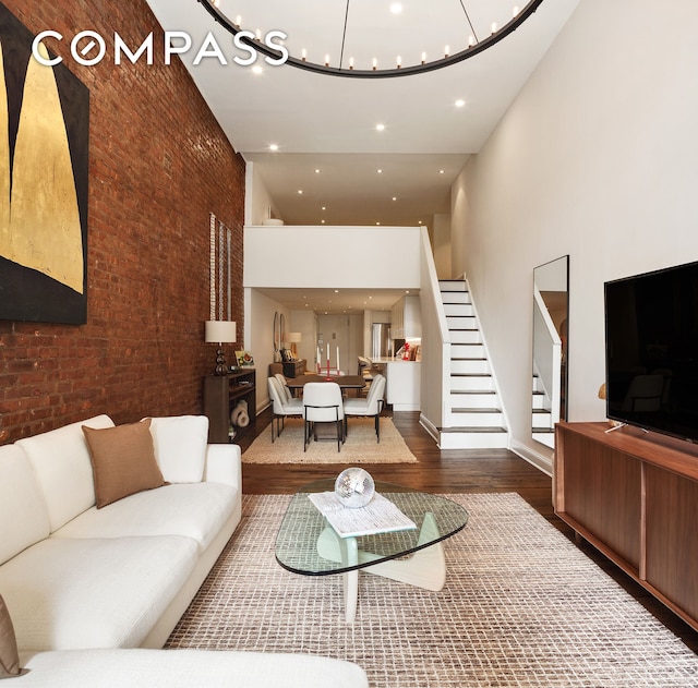 250 Mercer St Unit C302, New York City, NY 10012 - living area featuring a towering ceiling, wood finished floors, brick wall, stairs, and a chandelier