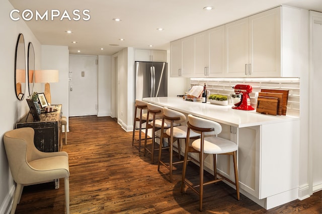250 Mercer St Unit C302, New York City, NY 10012 - kitchen featuring tasteful backsplash, dark wood-type flooring, white cabinets, a kitchen bar, and light countertops