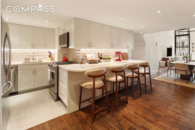 250 Mercer St Unit C302, New York City, NY 10012 - kitchen with appliances with stainless steel finishes, tasteful backsplash, a breakfast bar, light countertops, and recessed lighting