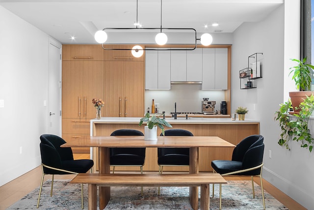 22-18 Jackson Ave Unit 208, New York City, NY 11101 - kitchen with hanging light fixtures, light countertops, white cabinetry, wood finished floors, and modern cabinets