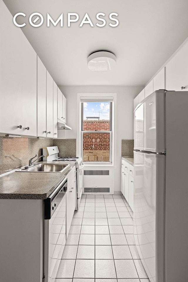 76-12 35th Ave Unit 6J, New York City, NY 11372 - kitchen featuring white appliances, radiator, tasteful backsplash, white cabinets, and light tile patterned flooring