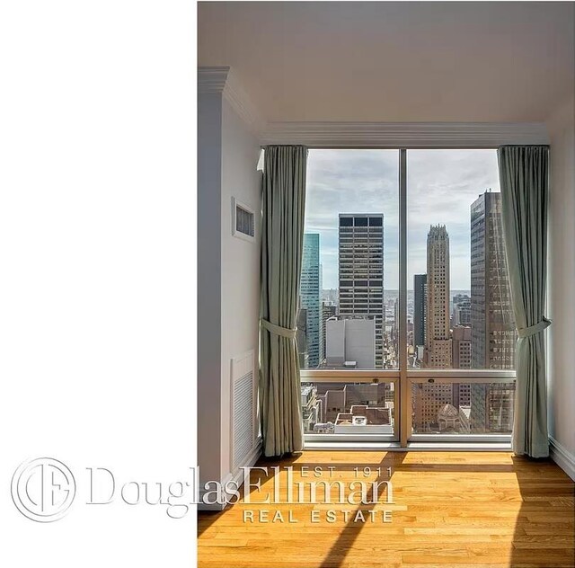 641 5th Ave Unit 35D, New York City, NY 10022 - empty room with wood finished floors, ornamental molding, and a skyline view