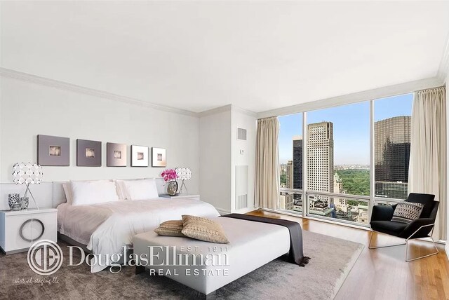 641 5th Ave Unit 35D, New York City, NY 10022 - bedroom with ornamental molding, wood finished floors, and floor to ceiling windows