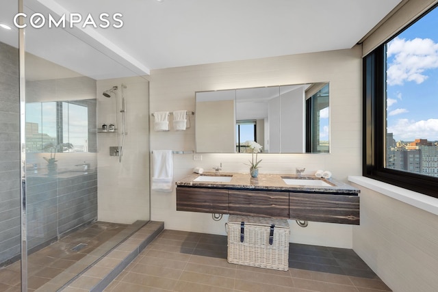 515 E 72nd St Unit 36B, New York City, NY 10021 - bathroom featuring a stall shower, double vanity, tile patterned floors, and tile walls