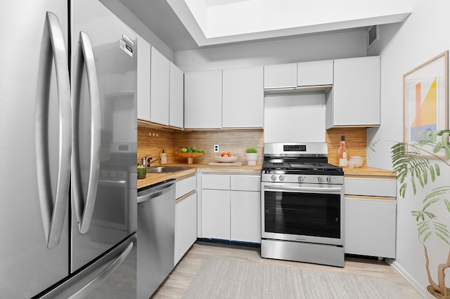 32 E 76th St Unit 605, New York City, NY 10021 - kitchen featuring appliances with stainless steel finishes, light countertops, decorative backsplash, and white cabinets