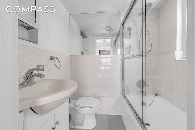 155 E 49th St Unit 3E, New York City, NY 10017 - full bathroom featuring tile patterned flooring, bath / shower combo with glass door, tile walls, and vanity