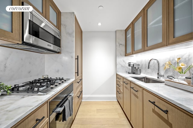 210 Warren St Unit 7F, New York City, NY 10282 - kitchen with stainless steel appliances, light wood finished floors, light stone counters, backsplash, and glass insert cabinets