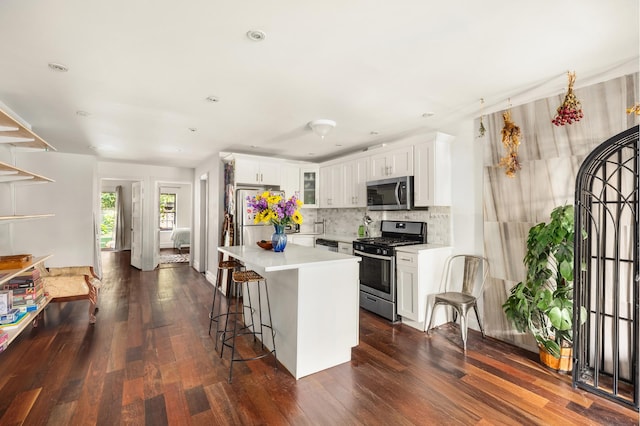127 Cooper St, New York City, NY 11207 - kitchen featuring stainless steel appliances, light countertops, tasteful backsplash, white cabinetry, and dark wood-style floors