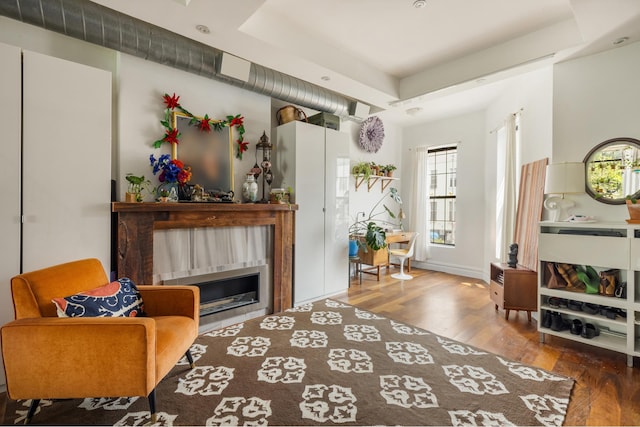 127 Cooper St, New York City, NY 11207 - sitting room featuring wood finished floors, a glass covered fireplace, and a raised ceiling