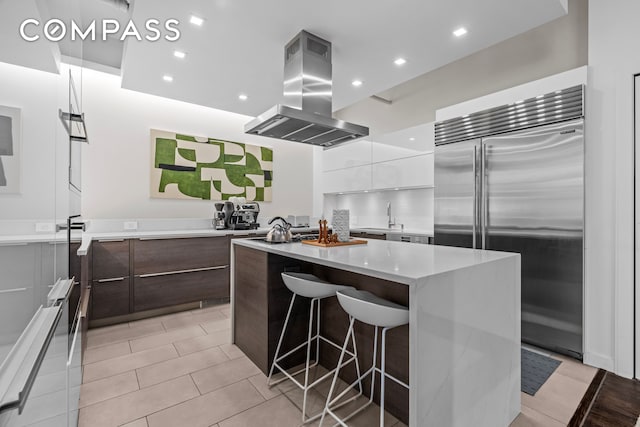 335 W 38th St Unit 6, New York City, NY 10018 - kitchen featuring stainless steel built in refrigerator, modern cabinets, island exhaust hood, white cabinets, and a center island