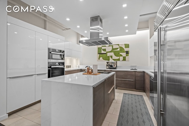 335 W 38th St Unit 6, New York City, NY 10018 - kitchen with appliances with stainless steel finishes, modern cabinets, island range hood, light tile patterned floors, and recessed lighting