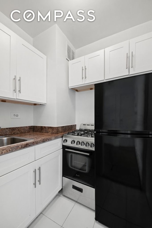 225 E 46th St Unit 2G, New York City, NY 10017 - kitchen featuring freestanding refrigerator, stainless steel gas range oven, white cabinetry, and dark countertops