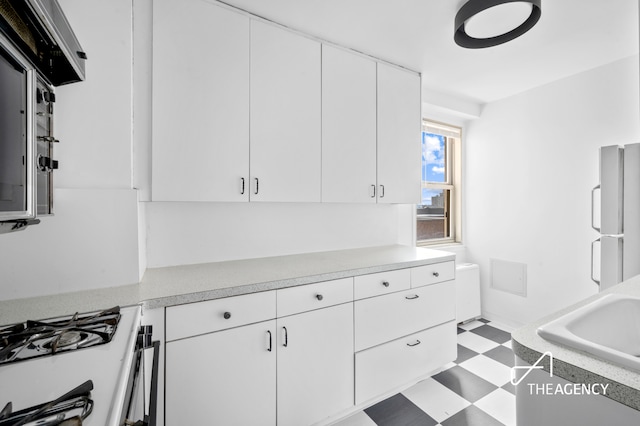 401 E 86th St Unit 8A, New York City, NY 10028 - kitchen with tile patterned floors, light countertops, freestanding refrigerator, and white cabinets