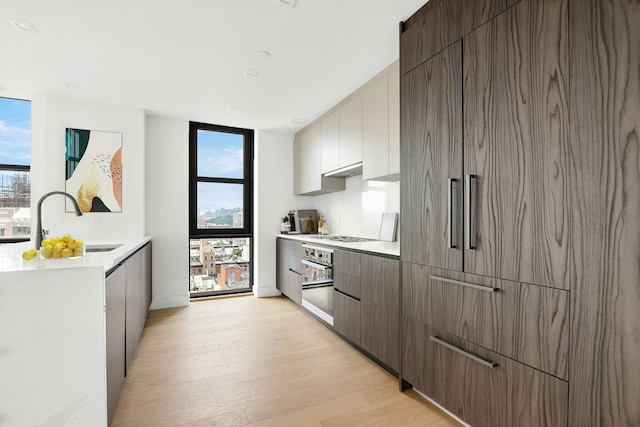 11 Hancock Pl Unit 708, New York City, NY 10027 - kitchen with modern cabinets, paneled fridge, stainless steel oven, light wood-style floors, and expansive windows