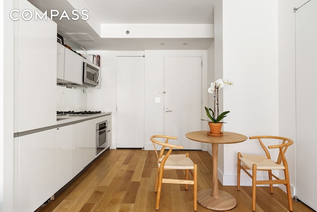 425 E 13th St Unit 3F, New York City, NY 10009 - kitchen featuring stainless steel appliances, white cabinets, light wood-style flooring, and modern cabinets