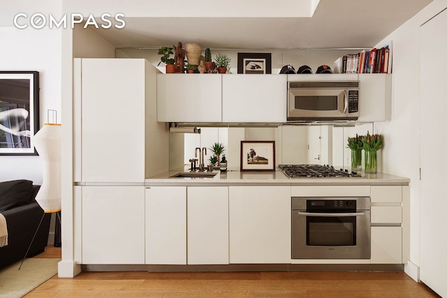 425 E 13th St Unit 3F, New York City, NY 10009 - kitchen with appliances with stainless steel finishes, light countertops, white cabinets, and light wood finished floors
