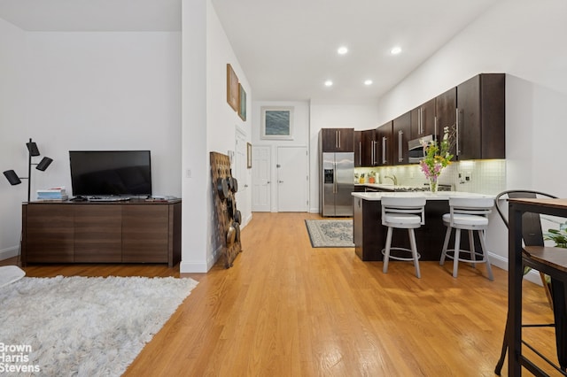 302 W 122nd St Unit 1, New York City, NY 10027 - kitchen with appliances with stainless steel finishes, a kitchen breakfast bar, light countertops, dark brown cabinets, and a peninsula