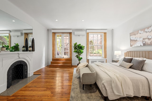 222 E 17th St Garden, Unit Garden, New York City, NY 10003 - bedroom with wood finished floors, an AC wall unit, radiator heating unit, recessed lighting, and a fireplace with flush hearth
