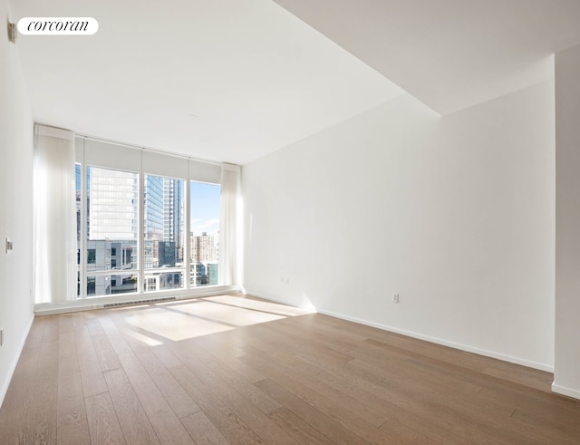 30 Riverside Blvd Unit 21G, New York City, NY 10069 - spare room featuring a wall of windows, wood-type flooring, and a city view