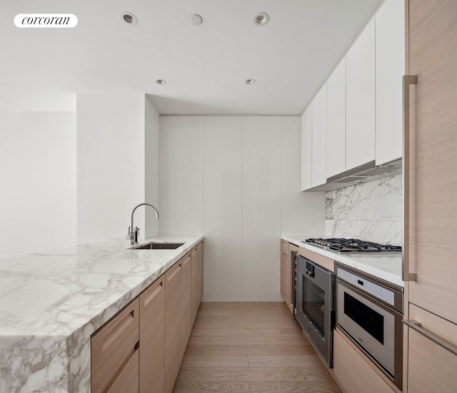 30 Riverside Blvd Unit 21G, New York City, NY 10069 - kitchen with stainless steel gas cooktop, oven, light wood-style floors, a peninsula, and backsplash