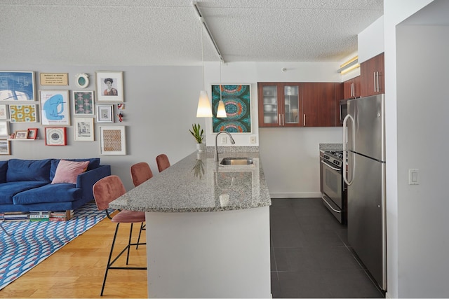 555 W 23rd St Unit N7H, New York City, NY 10011 - kitchen featuring a peninsula, a breakfast bar, stainless steel appliances, glass insert cabinets, and a textured ceiling