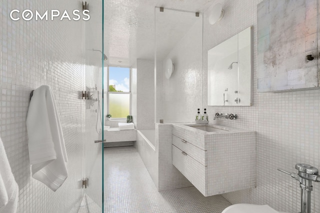 170 2nd Ave Unit 5A, New York City, NY 10003 - bathroom featuring tile walls, vanity, tile patterned flooring, a tub, and a shower with shower door