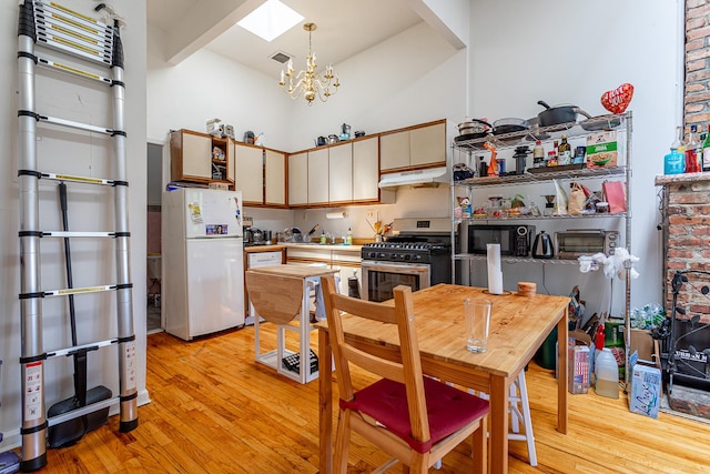 298 12th St Unit 4F, New York City, NY 11215 - kitchen featuring freestanding refrigerator, stainless steel range with gas stovetop, light wood-style floors, high vaulted ceiling, and a chandelier
